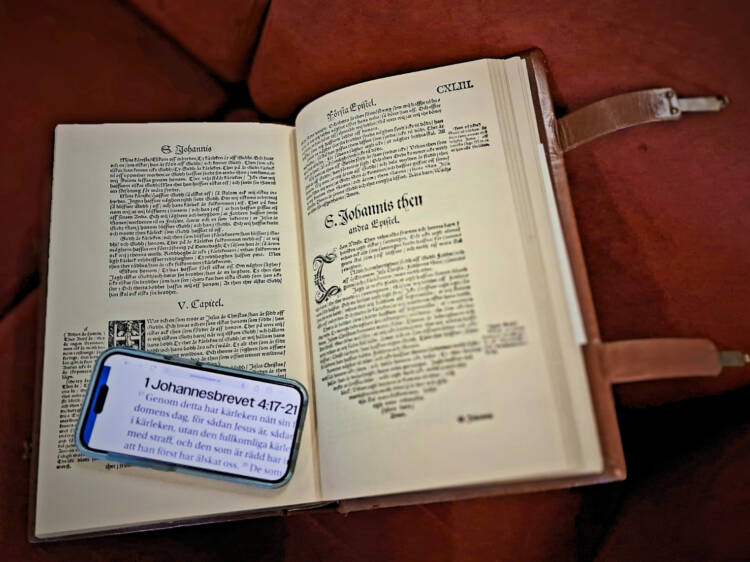 En gammal bibel uppslagen med en mobiltelefon liggande på den gamla texten.
